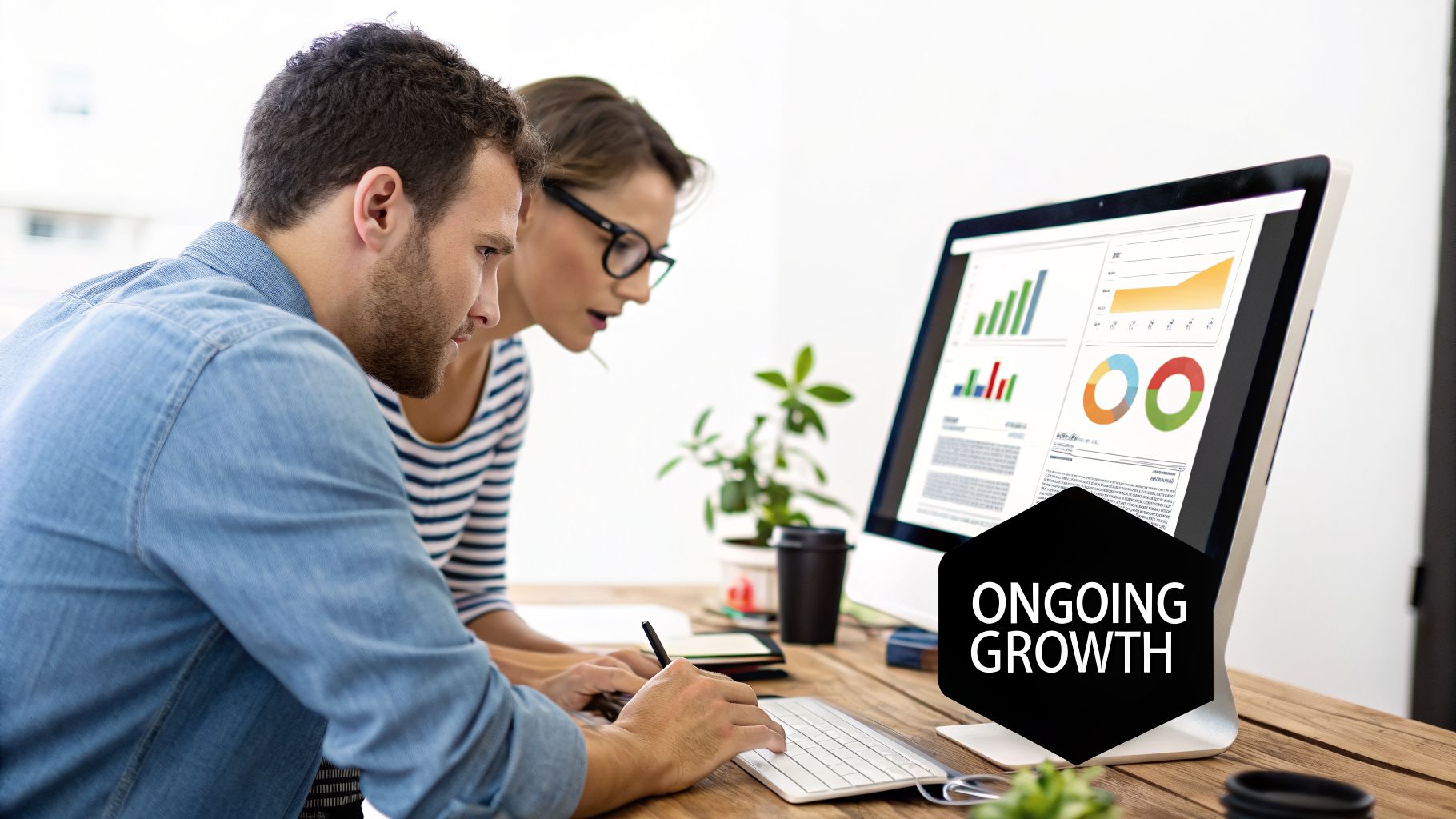 Two business professionals analyzing data on a computer screen displaying charts and graphs, with 'Ongoing Growth' text.