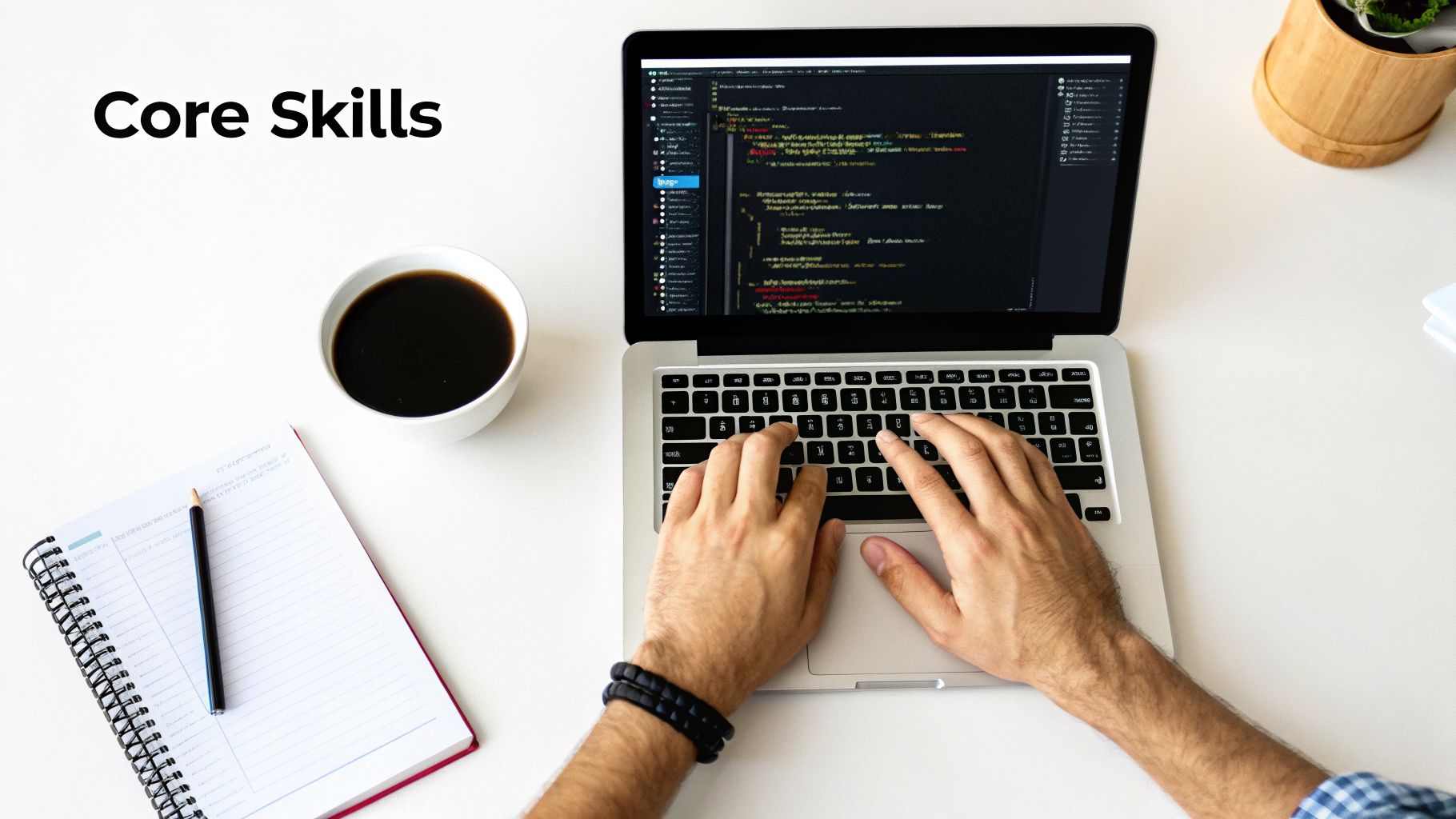 Overhead view of a person typing code on a laptop with coffee and a notebook, highlighting core skills.