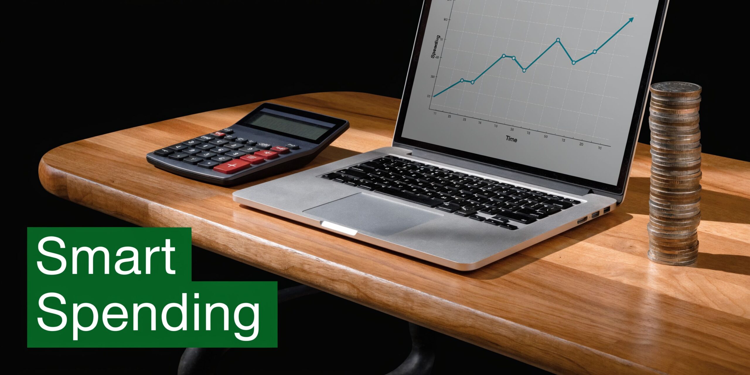 A laptop showing a financial growth chart, a calculator, and a stack of coins on a wooden desk.