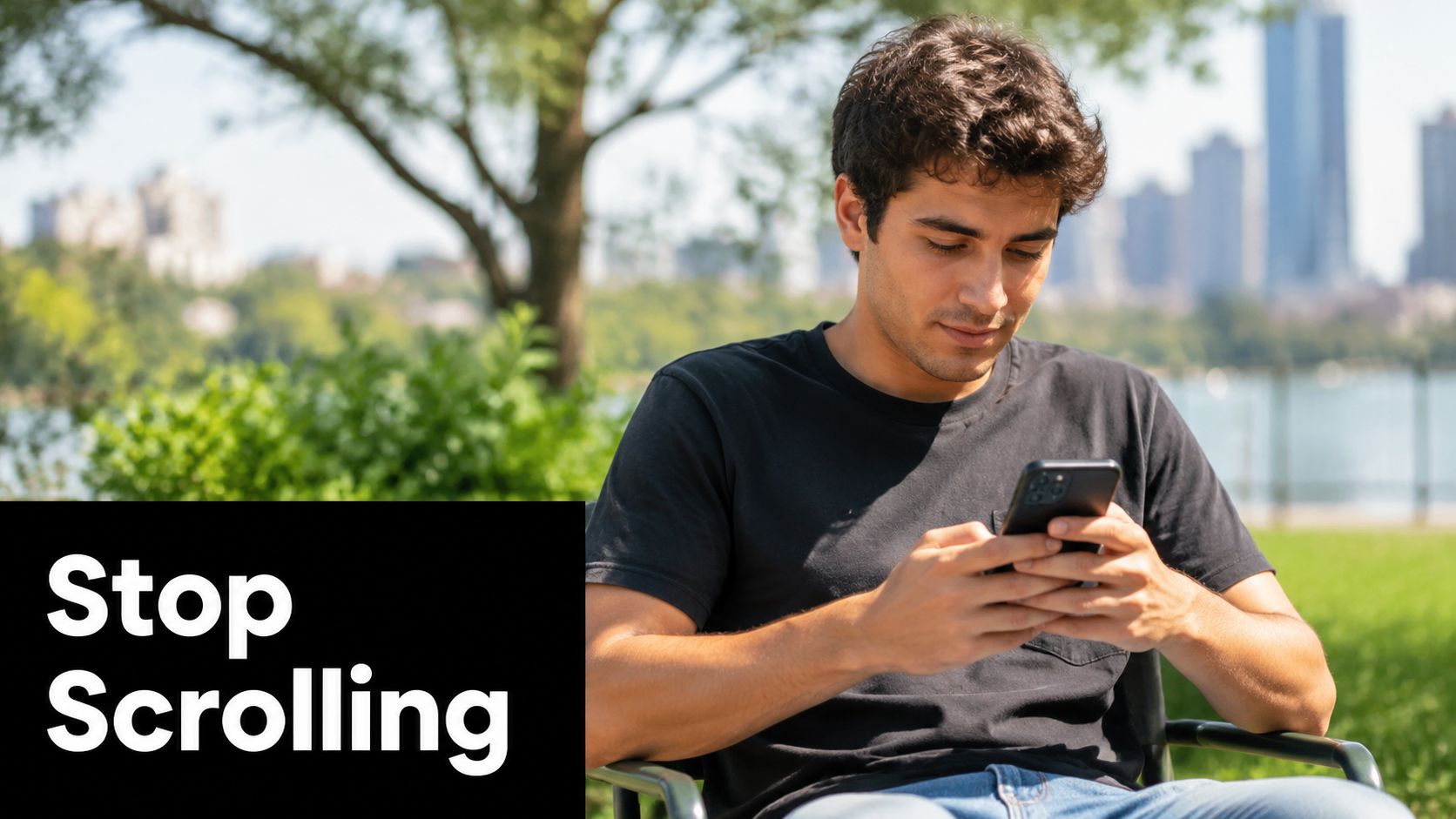 A young man sitting in a park while looking down at his smartphone in his hands.
